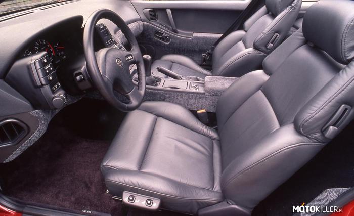 1990 Nissan 300ZX Z32 - Ciekawe wnętrza #19 – Nie mogło tu zabraknąć mojego ulubionego modelu Nissana. Mocno pochylona środkowa konsola, wysoko poprowadzony tunel i płynna linia utworzona przez kokpit i boczki drzwi. Przyciski do obsługi świateł i sterowania klimatyzacją są umieszczone na panelach po bokach zestawu zegarów. Ciekawostką są pasy bezpieczeństwa całkowicie wbudowane w drzwi. Pasy da się zapiąć oraz odpiąć tylko wtedy, gdy drzwi są zamknięte. 